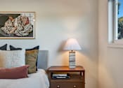 Thumbnail 14 of 39 - A bedroom with a bed, a nightstand with a lamp and a painting on the wall.