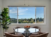 Thumbnail 8 of 39 - A table with a bowl of fruit on it sits in front of a window with a view of the outdoors.