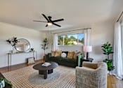 Thumbnail 6 of 39 - A living room with a green couch, a coffee table, and a ceiling fan.