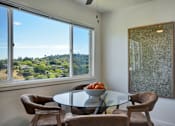Thumbnail 5 of 39 - A dining room with a glass table and chairs and a view of the outdoors through the window.