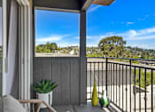 Thumbnail 23 of 39 - A balcony with a chair, a table, and a potted plant overlooks a residential area.