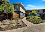 Thumbnail 2 of 39 - A modern apartment complex with a landscaped garden in front.