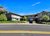 Thumbnail 1 of 39 - A large apartment complex with a parking lot in front.