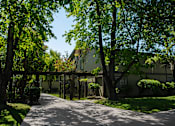 Thumbnail 1 of 27 - A tree-lined pathway leads to a building.