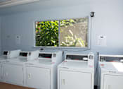 Thumbnail 24 of 27 - A row of white washing machines are lined up in a room.
