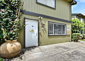 Thumbnail 27 of 27 - A green house with a white door and a large pot in front.