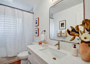 Thumbnail 16 of 27 - A bathroom with a white sink and a large mirror.