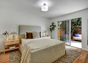 Thumbnail 18 of 27 - A bedroom with a large bed and a sliding glass door.