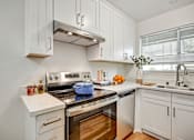 Thumbnail 9 of 27 - A modern kitchen with white cabinets and stainless steel appliances.