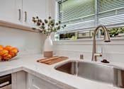 Thumbnail 8 of 27 - A kitchen with a white sink and a vase of flowers.
