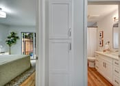Thumbnail 14 of 27 - A white door opens to a bathroom with a sink and mirror.