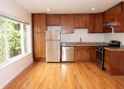 Thumbnail 6 of 8 - A kitchen with wooden cabinets and a stainless steel refrigerator.