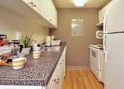 Thumbnail 16 of 18 - A kitchen with a granite countertop and white appliances.
