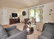 Thumbnail 9 of 18 - A living room with grey couches and a wooden coffee table.