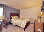 Thumbnail 12 of 18 - A bedroom with a bed, nightstand, and window.