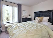 Thumbnail 17 of 18 - A bed with a yellow comforter and a black headboard.