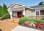 Thumbnail 1 of 18 - A house with a red door and a stone wall.