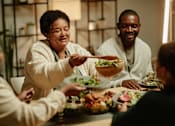 Thumbnail 5 of 9 - A group of people are gathered around a table enjoying a meal together.