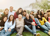 Thumbnail 6 of 9 - A group of people sitting on the grass in a park.