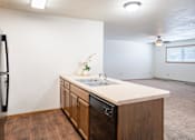Thumbnail 12 of 18 - A kitchen with a sink, refrigerator, and wooden cabinets. Fargo, ND Cedars 4 Apartments