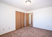 Thumbnail 41 of 44 - A room with a carpeted floor and a white wall with a brown door and a brown wardrobe.