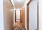 Thumbnail 42 of 44 - A hallway with wooden doors and carpeted floor.