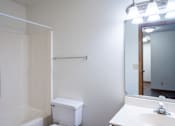Thumbnail 8 of 13 - A white bathroom with a toilet, sink, and mirror. Fargo, ND Candlelight Apartments