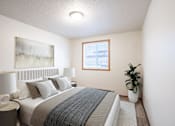 Thumbnail 3 of 13 - A bedroom with a bed, nightstand, and a plant. Fargo, ND Candlelight Apartments