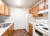 Thumbnail 5 of 13 - A kitchen with wooden cabinets and white appliances. Fargo, ND Candlelight Apartments