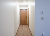 Thumbnail 12 of 13 - A long hallway with a brown door at the end. Fargo, ND Candlelight Apartments