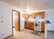 Thumbnail 10 of 13 - A kitchen with wooden cabinets and a white stove. Fargo, ND Candlelight Apartments