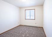Thumbnail 25 of 44 - A room with a window and a carpeted floor. Fargo, ND Country Edge Apartments