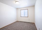 Thumbnail 23 of 44 - A room with a window and a carpeted floor. Fargo, ND Country Edge Apartments