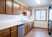 Thumbnail 12 of 23 - A kitchen with wooden cabinets and a dishwasher. Fargo, ND Somerset Apartments
