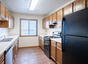 Thumbnail 13 of 23 - A kitchen with wooden cabinets and a black refrigerator. Fargo, ND Somerset Apartments