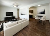 Thumbnail 5 of 11 - A living room with a white couch and a television. Bismarck, ND Belmont West Apartments