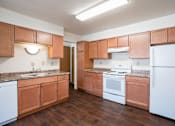 Thumbnail 11 of 16 - A kitchen with wooden cabinets and white appliances. Fargo, ND Birchwood 2 Apartments