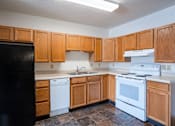 Thumbnail 17 of 21 - A kitchen with wooden cabinets and black appliances. Dilworth, MN Fieldstone Apartments