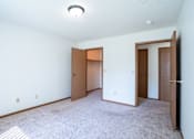 Thumbnail 12 of 30 - A room with two doors and a carpeted floor.