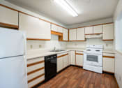 Thumbnail 9 of 30 - A white refrigerator is in a kitchen with wooden floors and white cabinets.