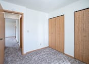Thumbnail 16 of 20 - A room with a carpeted floor and a white wall with a door and a window. West Fargo, ND Saddlebrook Apartments