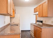 Thumbnail 12 of 20 - A kitchen with wooden cabinets and a granite countertop. West Fargo, ND Saddlebrook Apartments
