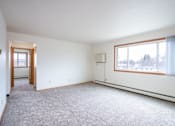 Thumbnail 10 of 20 - A large, empty room with a carpeted floor and a window with curtains. West Fargo, ND Saddlebrook Apartments