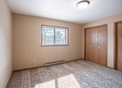 Thumbnail 6 of 13 - A room with a window, carpet, and two doors.