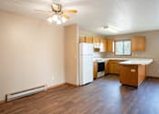 Thumbnail 4 of 13 - A kitchen with wooden floors and a ceiling fan.