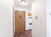 Thumbnail 16 of 17 - A white hallway with a brown door leading to a kitchen. Fargo, ND Fieldstone Apartments