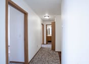 Thumbnail 15 of 17 - A long hallway with a carpeted floor and white walls. Fargo, ND Fieldstone Apartments