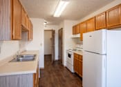 Thumbnail 7 of 17 - A kitchen with a white refrigerator, sink, and wooden cabinets. Fargo, ND Fieldstone Apartments