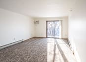 Thumbnail 6 of 17 - A room with a carpeted floor and a sliding glass door leading outside. Fargo, ND Fieldstone Apartments