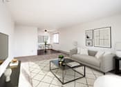 Thumbnail 2 of 17 - A living room with a grey couch, a black coffee table, and a television on the left side. Fargo, ND Fieldstone Apartments
